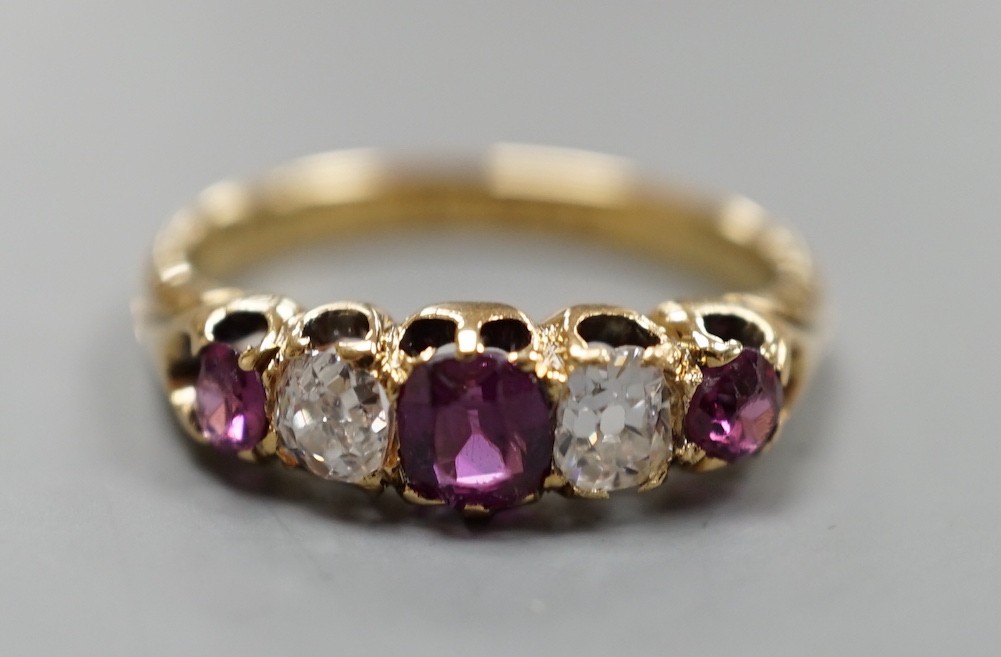 An 18ct gold, three stone ruby and two stone diamond set half hoop ring, size O, gross weight 3.7 grams.